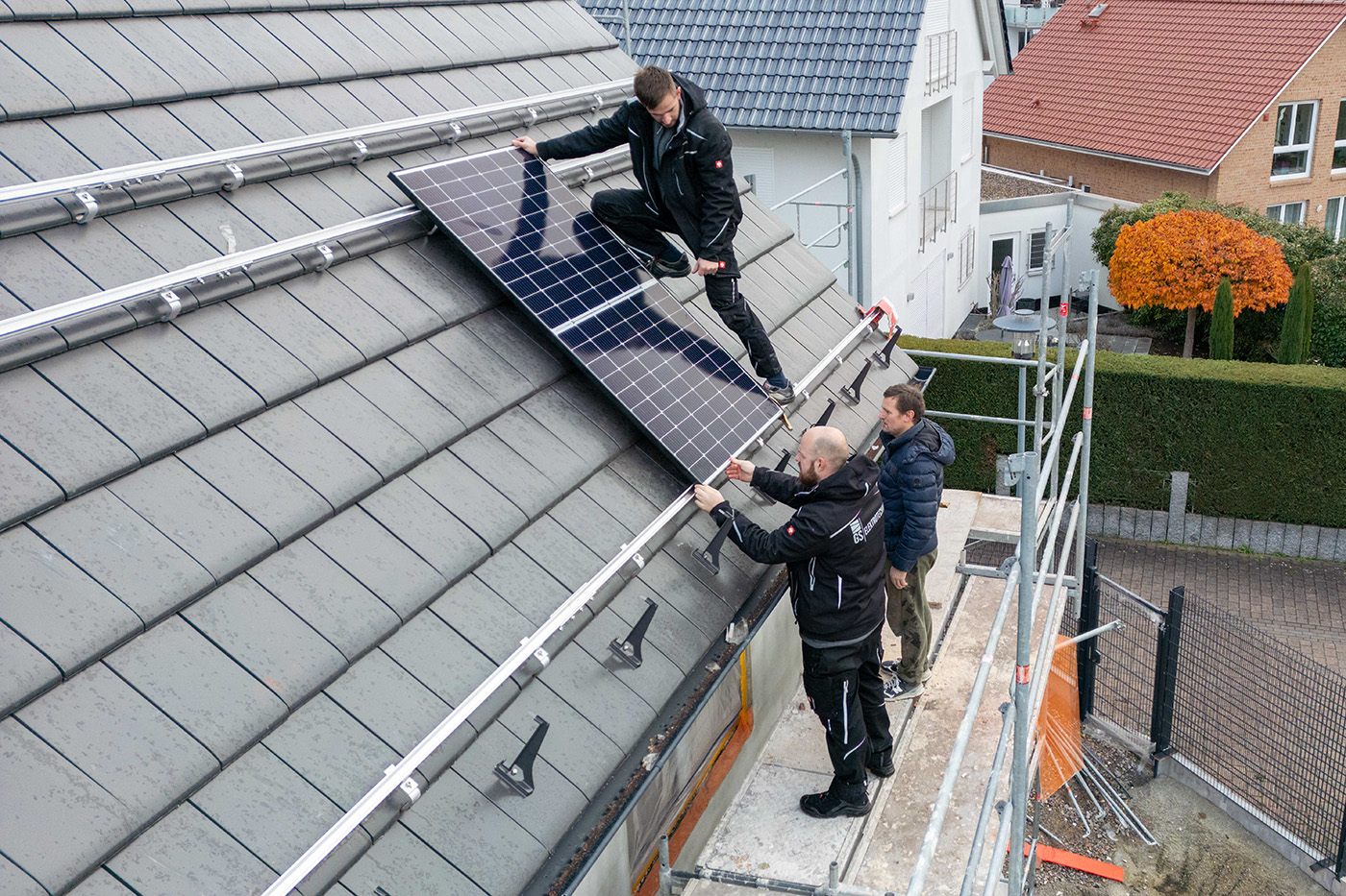 Handwerker montieren Photovoltaikmodule auf einem Hausdach
